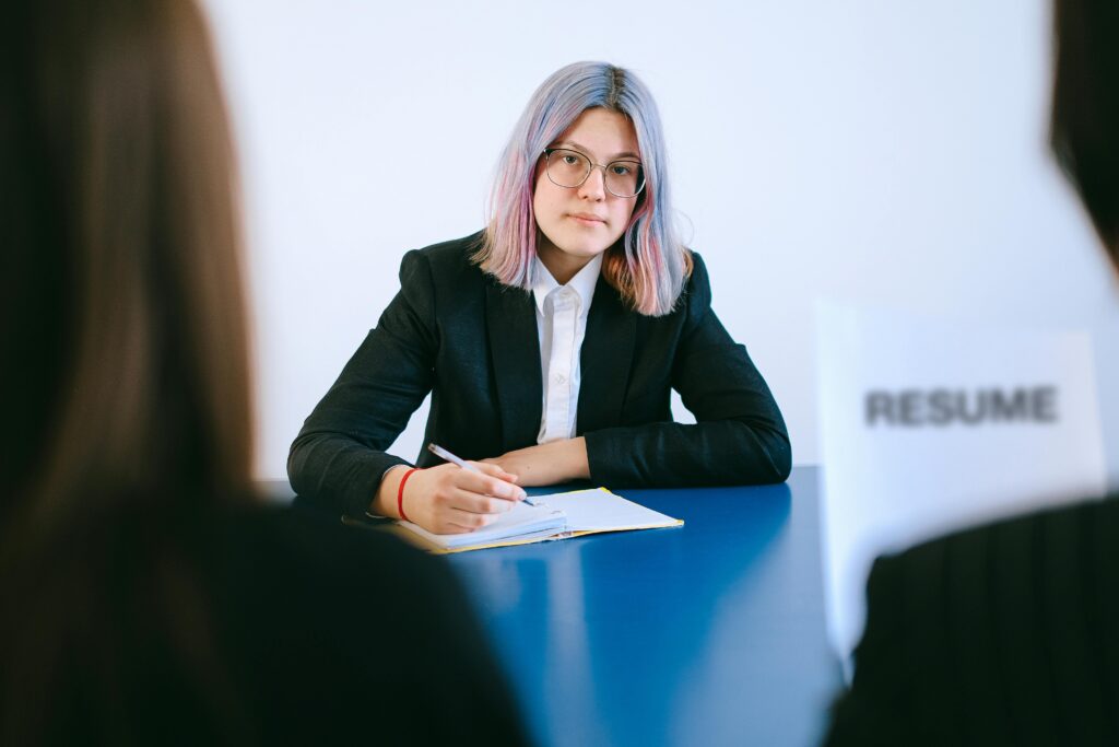 About A young woman with dyed hair takes notes during a job interview.